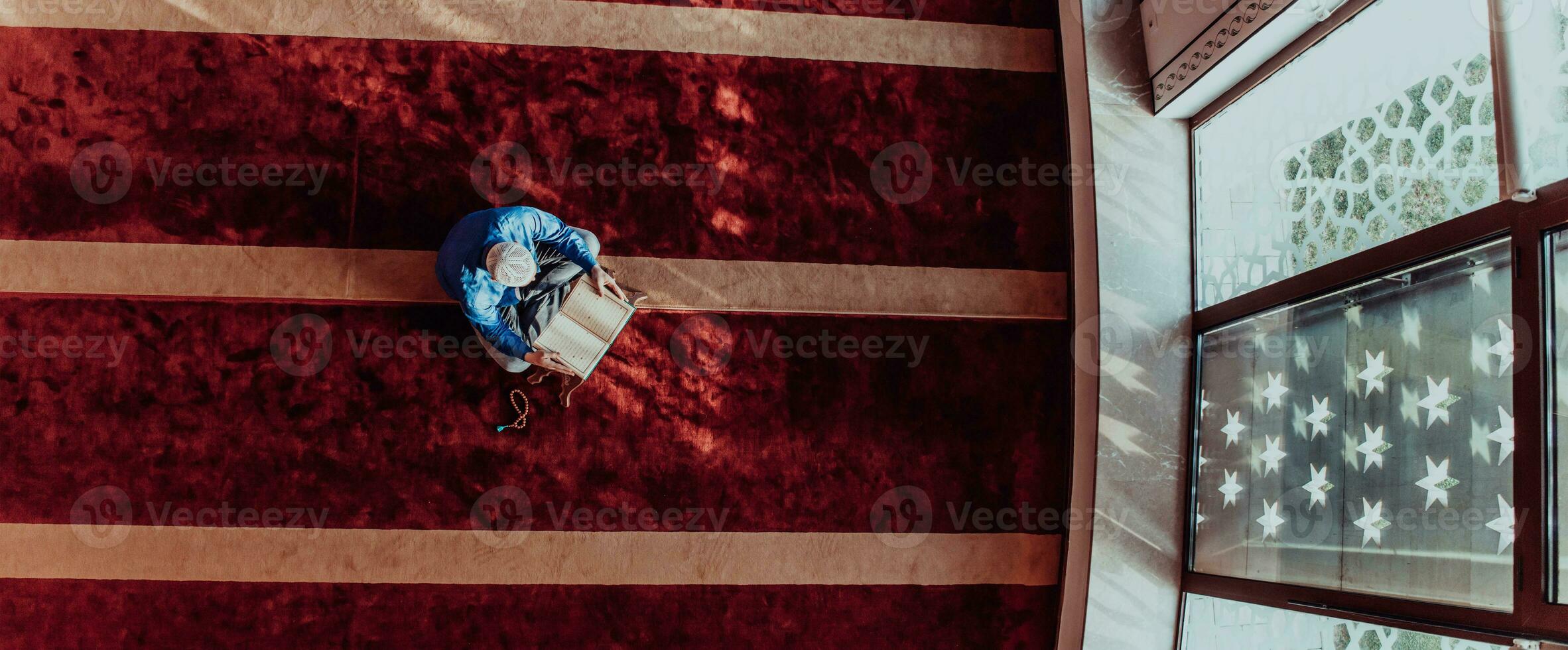 A Muslim reads the holy Islamic book Quraqn in a modern grand mosque during the Muslim holy month of Ranazan photo