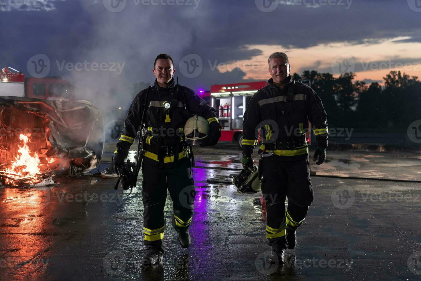 Brave Firefighters Team Walking to the Camera. In Background Paramedics and Firemen Rescue Team Fight Fire in Car Accident, Insurance and Save Peoples Lives concept. photo
