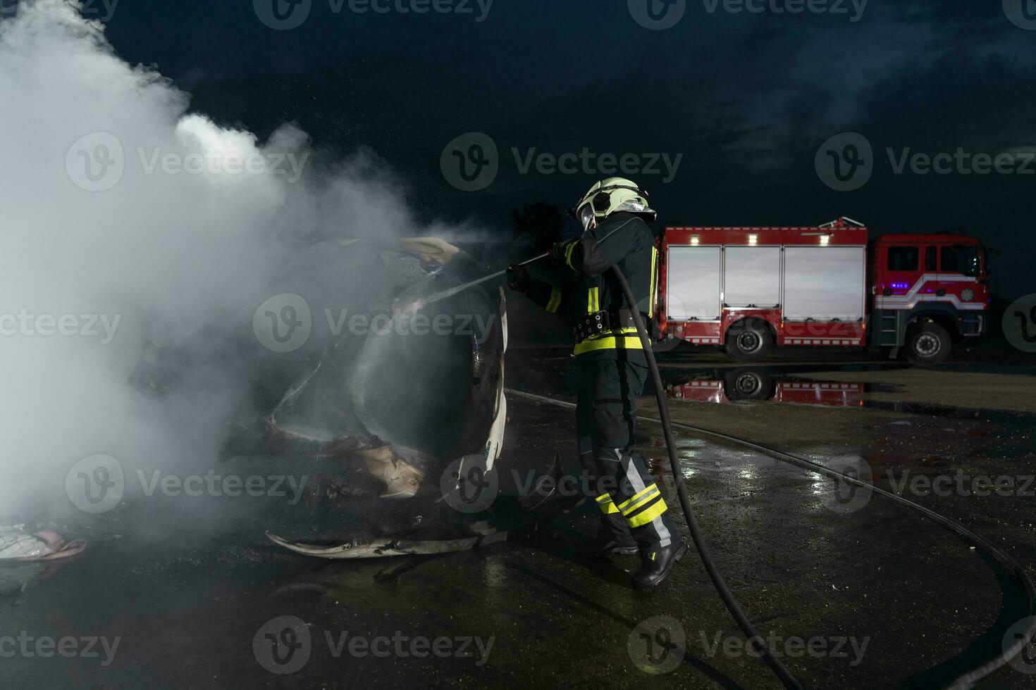 Firefighters using water fire extinguisher to fighting with the fire flame in car accident. Firefighter industrial and public safety concept rescue in night. photo