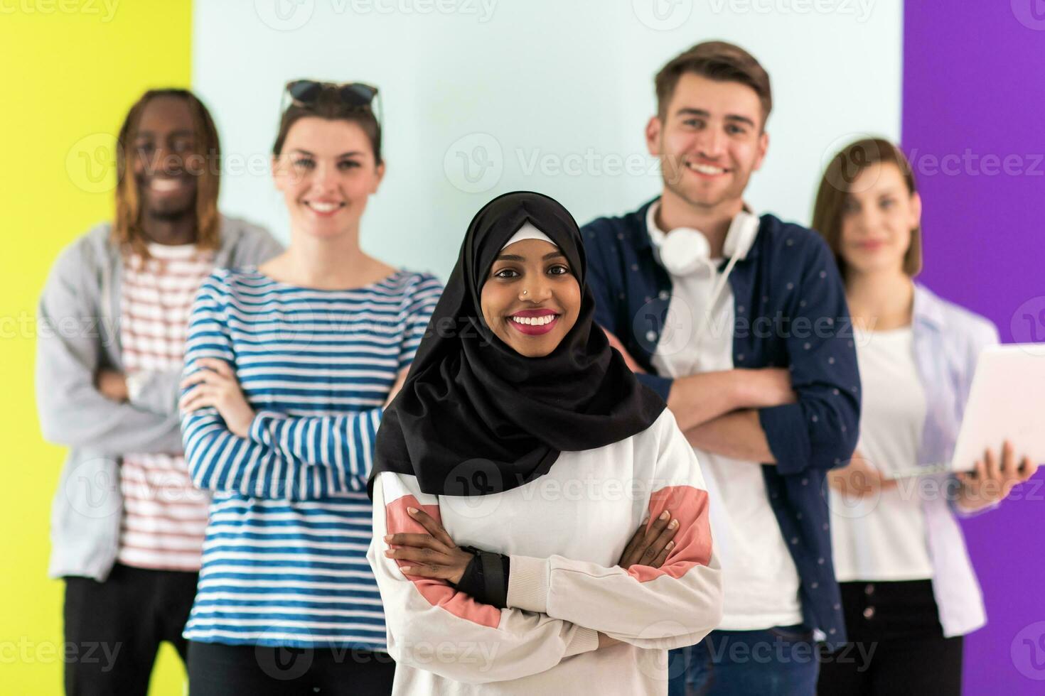 Diverse teenagers using mobile devices while posing for a studio photo in front of a colorful background