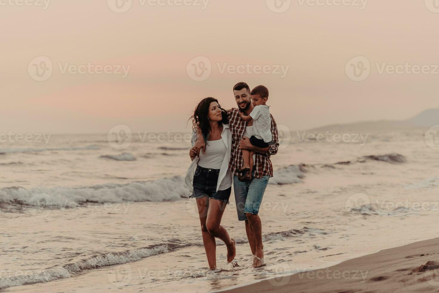 The family enjoys their vacation as they walk the sandy beach with their son. Selective focus photo