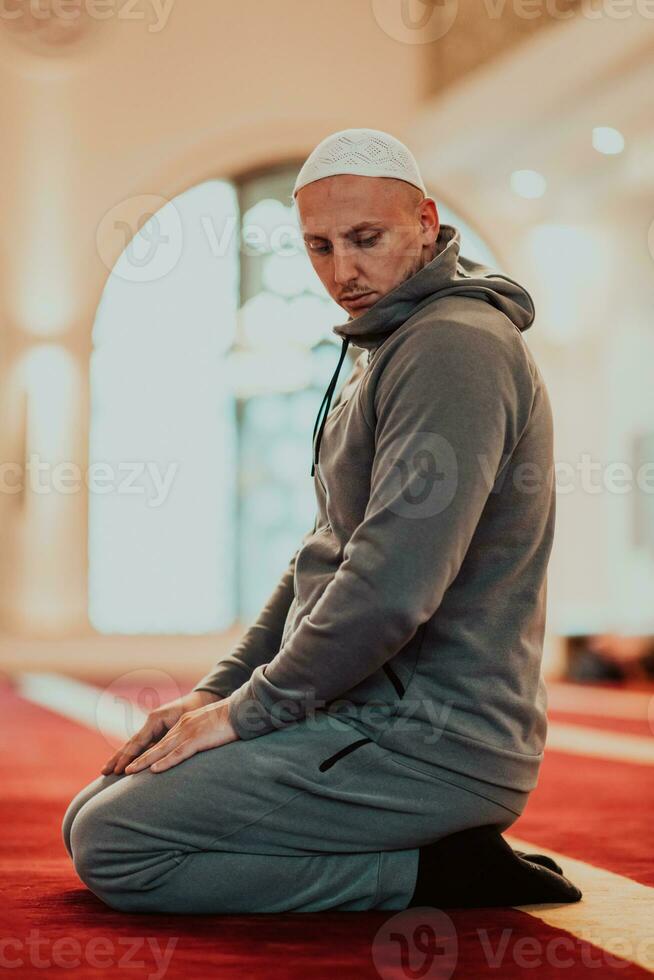 A Muslim praying in a modern mosque during the holy Muslim month of Ramadan photo