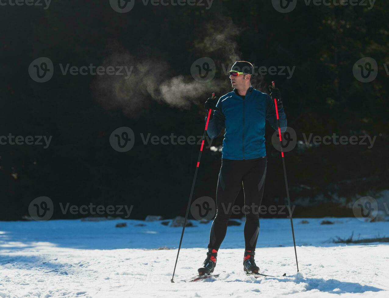 Portrait handsome male athlete with cross country skis, taking fresh breath and having break after hard workout training in a snowy forest. Healthy winter lifestyle concept photo