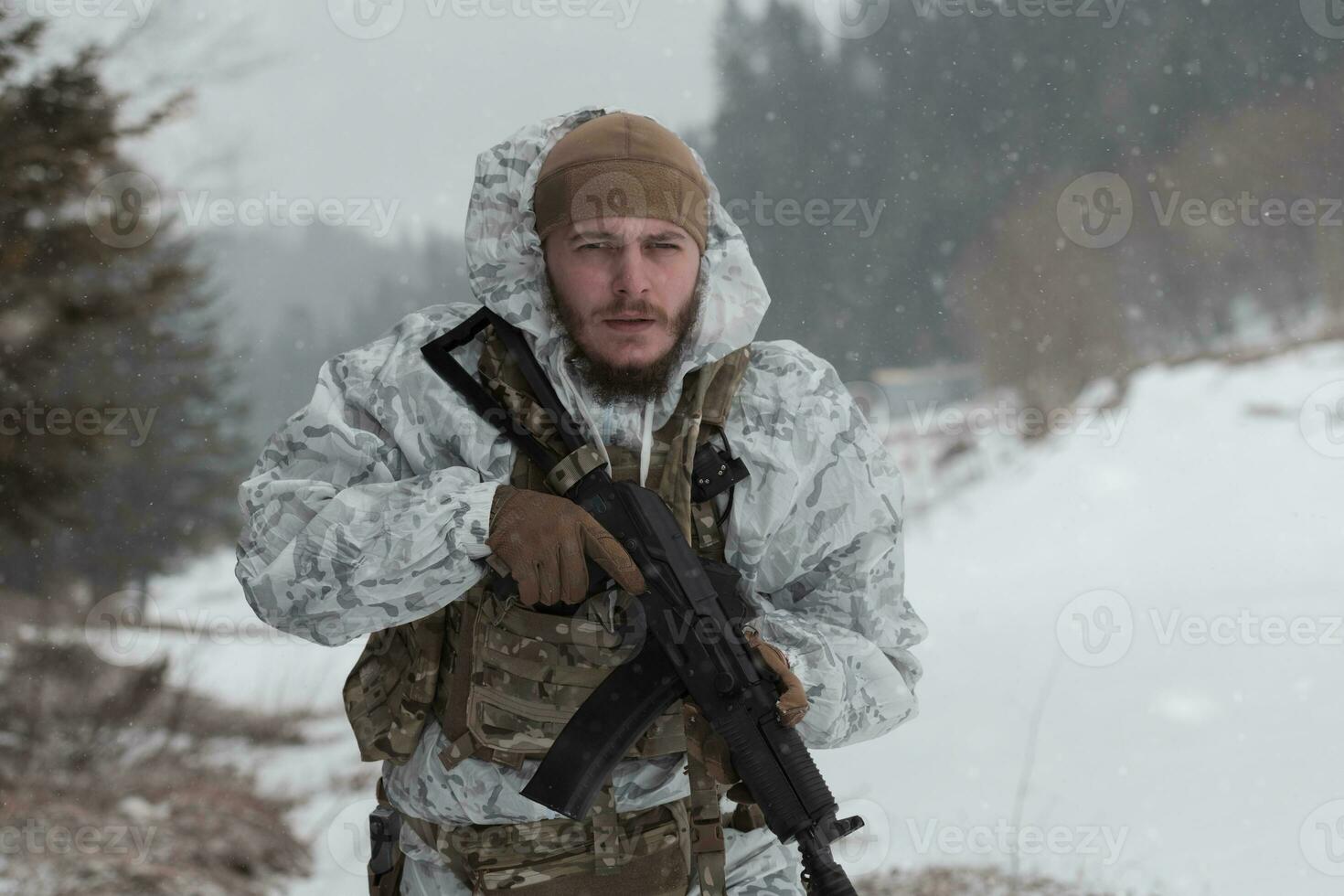 Winter war in the Arctic mountains. Operation in cold conditions.Soldier in winter camouflaged uniform in Modern warfare army on a snow day on forest battlefield with a rifle. Selective focus photo