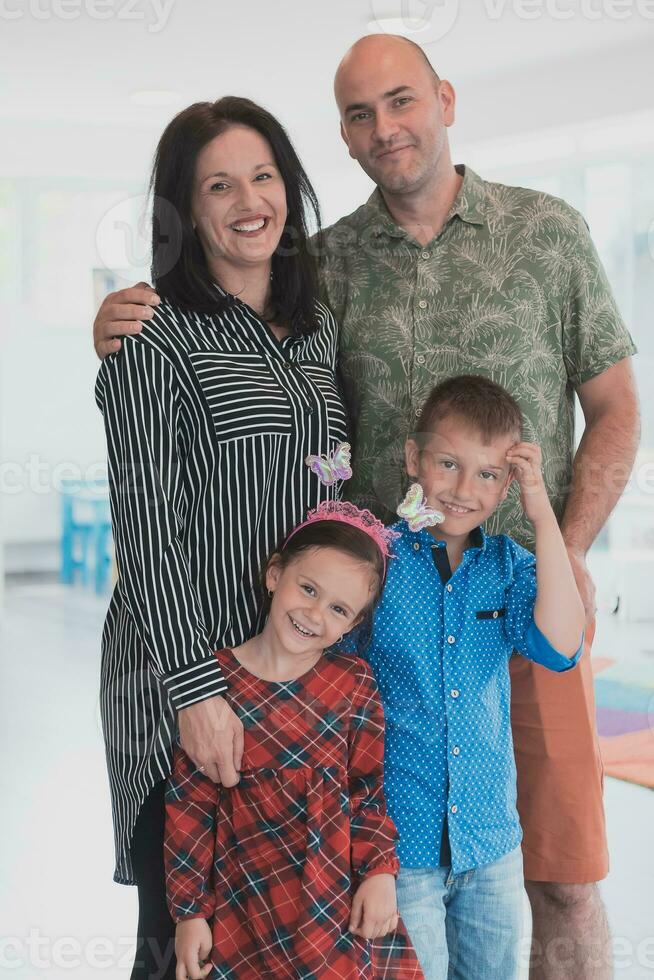 retrato de un contento familia. foto de padres con niños en un moderno preescolar aula. selectivo atención