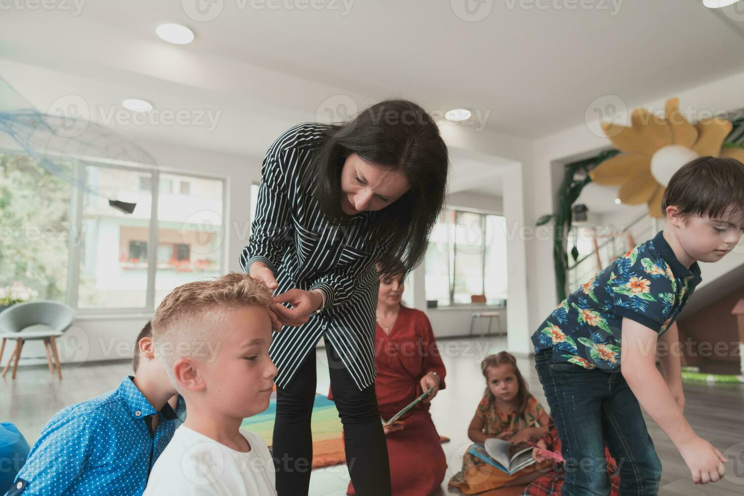 The teacher takes care of the children in the preschool institution photo