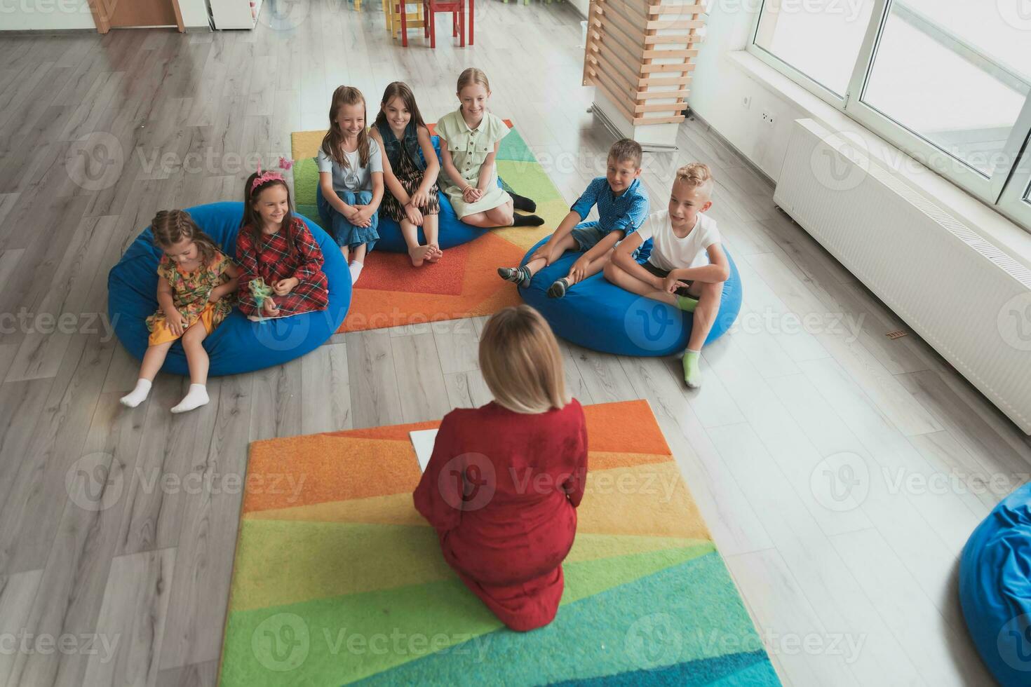Reading time in an elementary school or kindergarten, a teacher reads a book to children in an elementary school or kindergarten. The concept of pre-school education. Selective focus photo