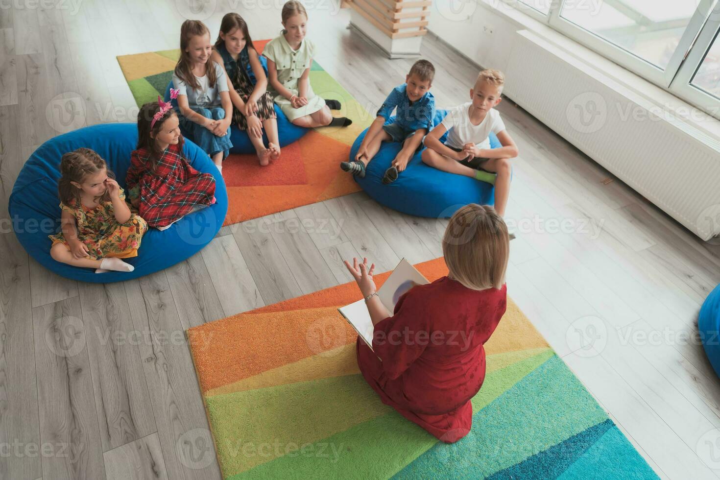 Reading time in an elementary school or kindergarten, a teacher reads a book to children in an elementary school or kindergarten. The concept of pre-school education. Selective focus photo