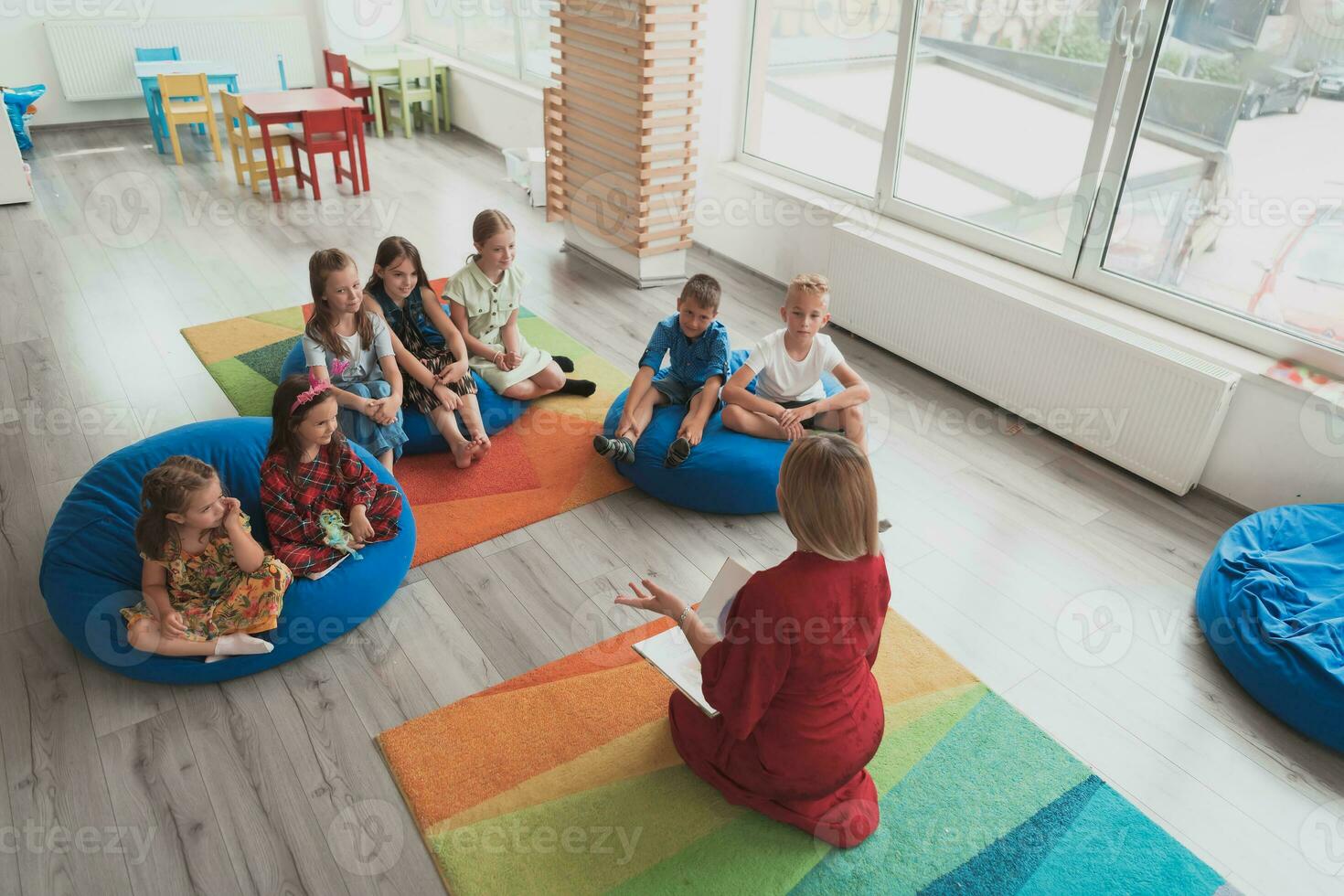 Reading time in an elementary school or kindergarten, a teacher reads a book to children in an elementary school or kindergarten. The concept of pre-school education. Selective focus photo