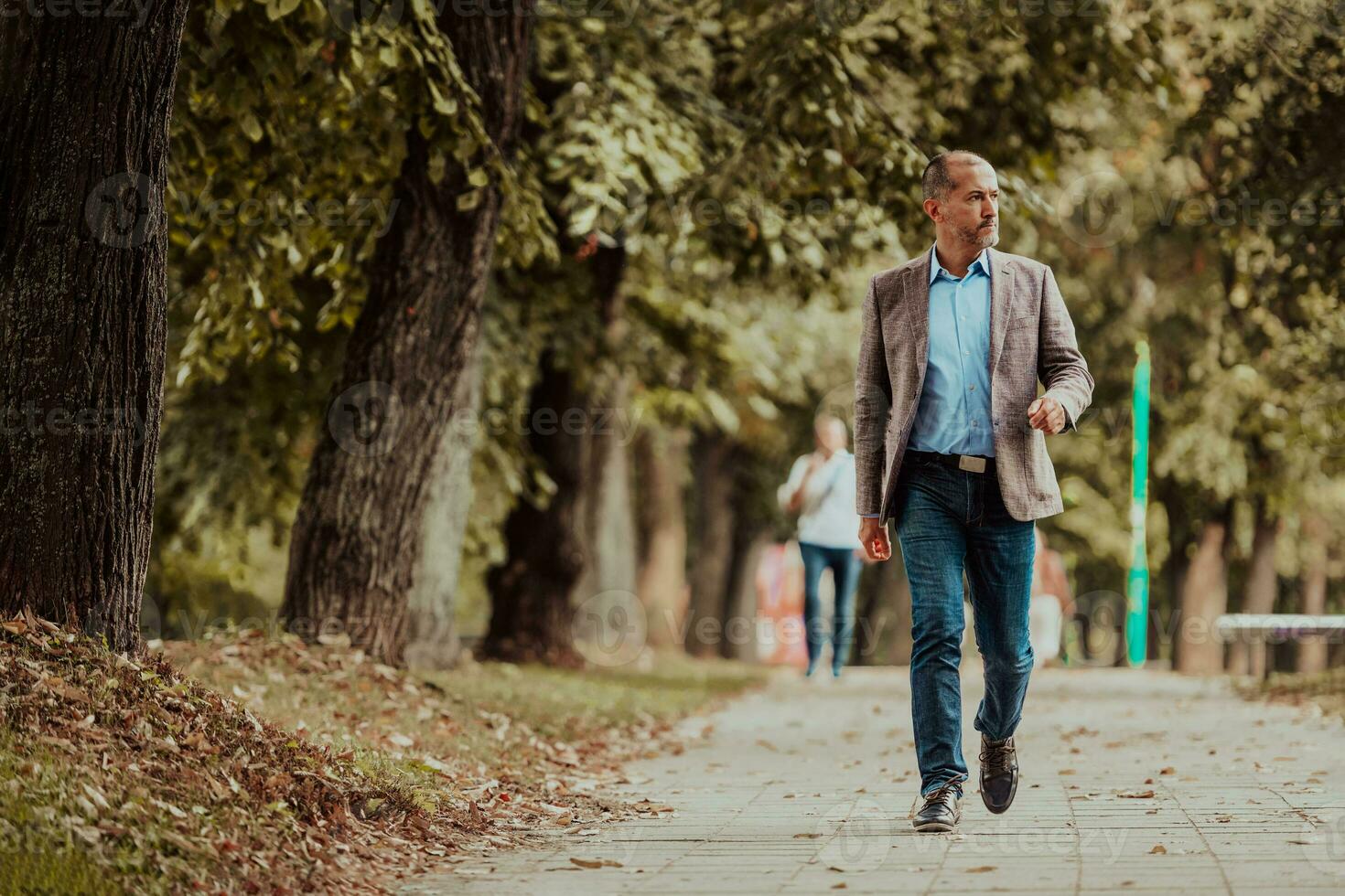 Focused businessman in a suit walking in the park photo
