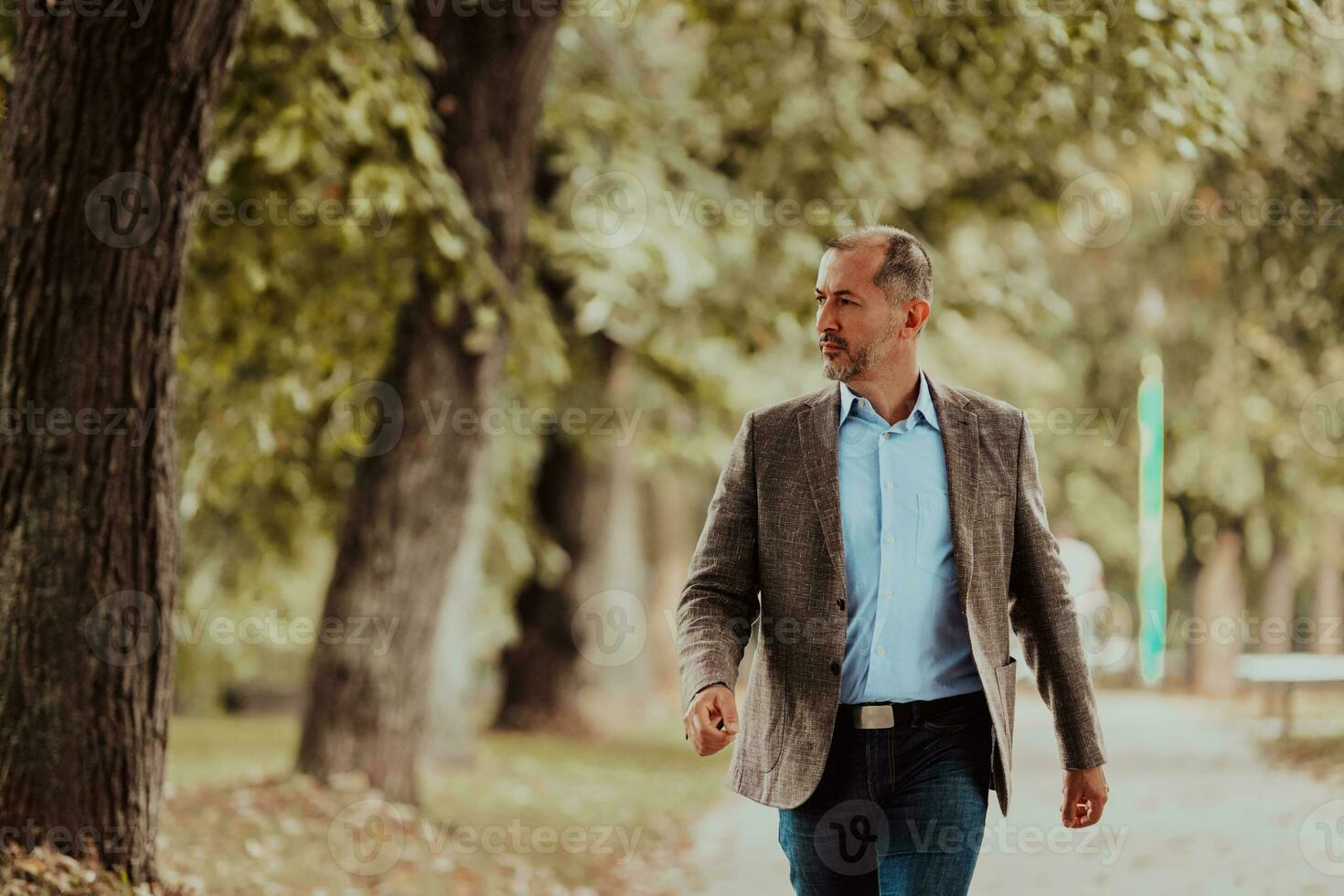 Focused businessman in a suit walking in the park photo