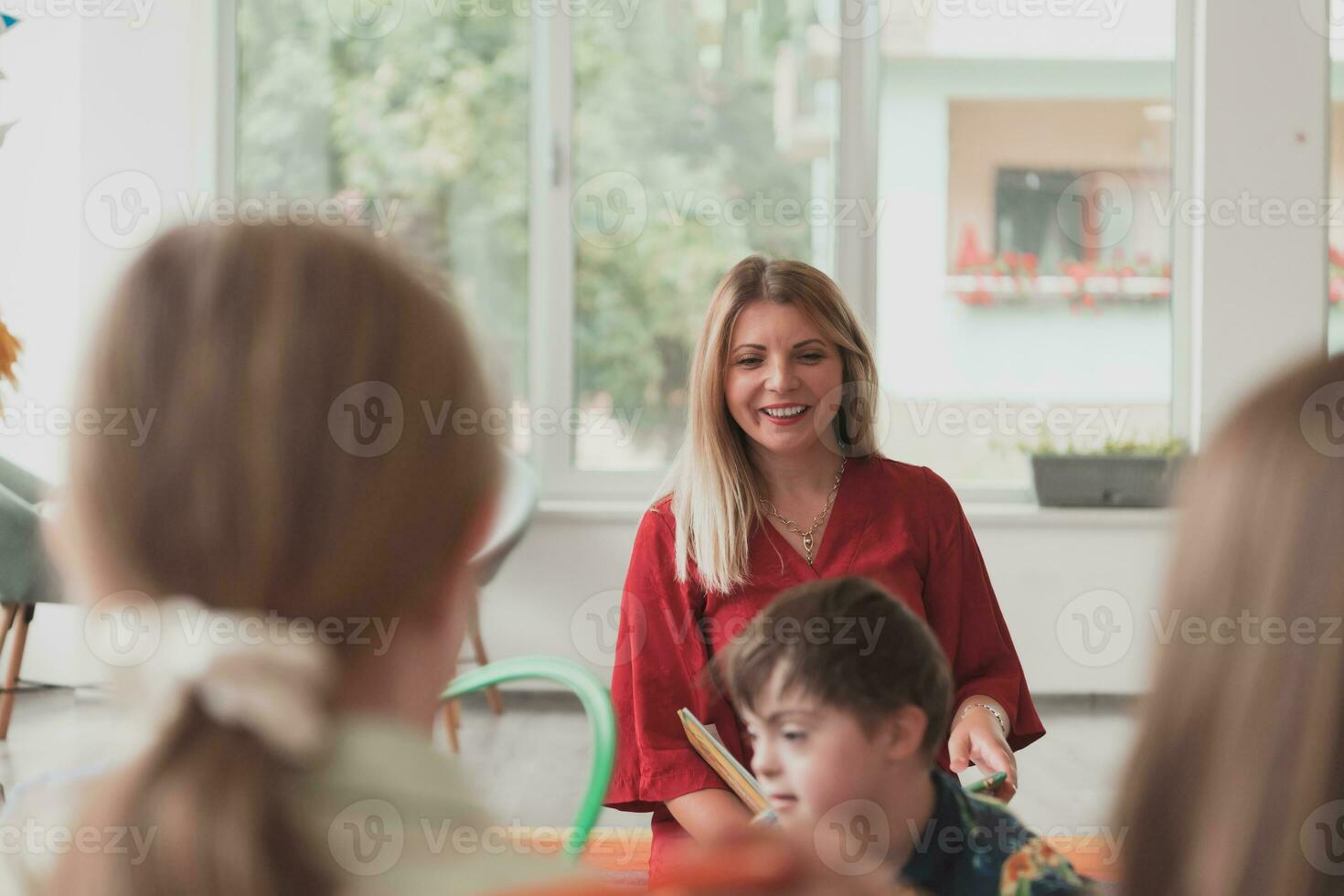 Reading time in an elementary school or kindergarten, a teacher reads a book to children in an elementary school or kindergarten. The concept of pre-school education. Selective focus photo