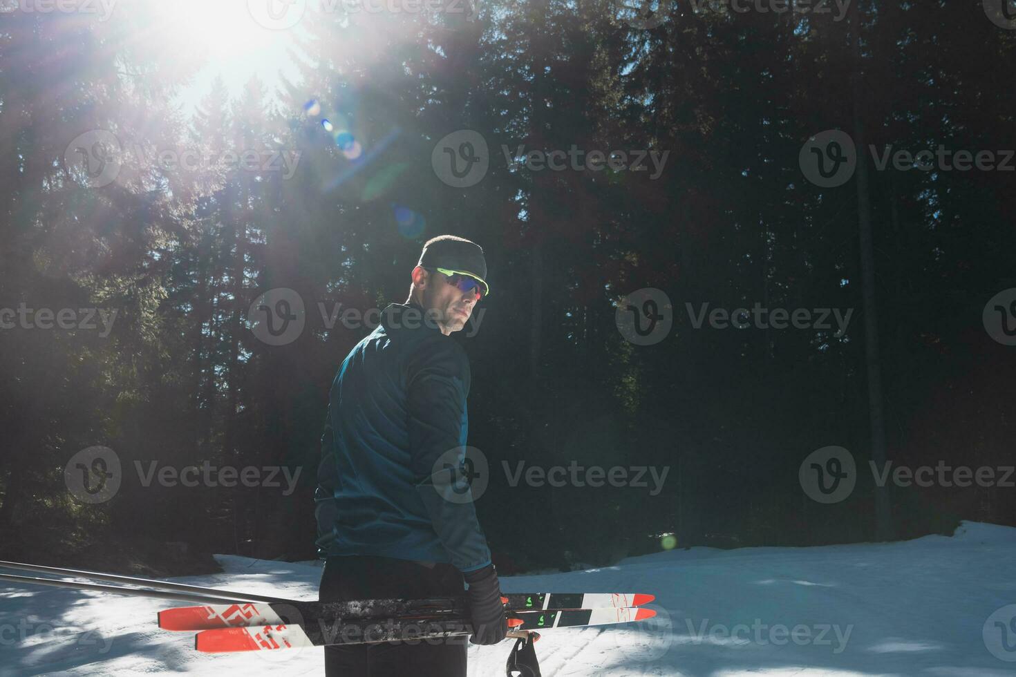 retrato hermoso masculino atleta con cruzar país esquís en manos y gafas de protección, formación en Nevado bosque. sano invierno estilo de vida concepto. foto