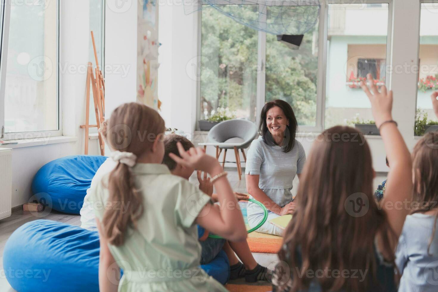 Reading time in an elementary school or kindergarten, a teacher reads a book to children in an elementary school or kindergarten. The concept of pre-school education. Selective focus photo