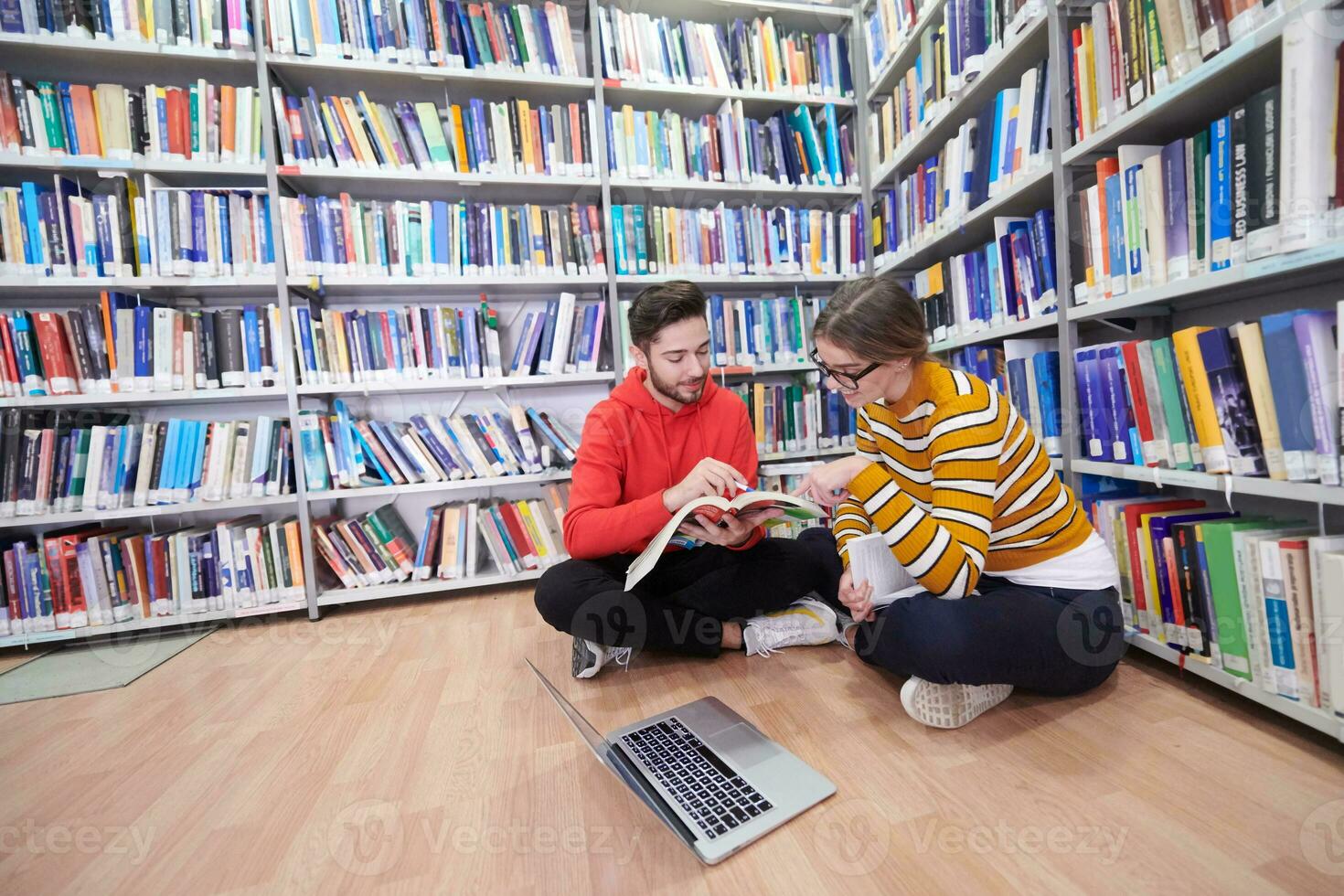 the students uses a notebook, laptop and a school library photo