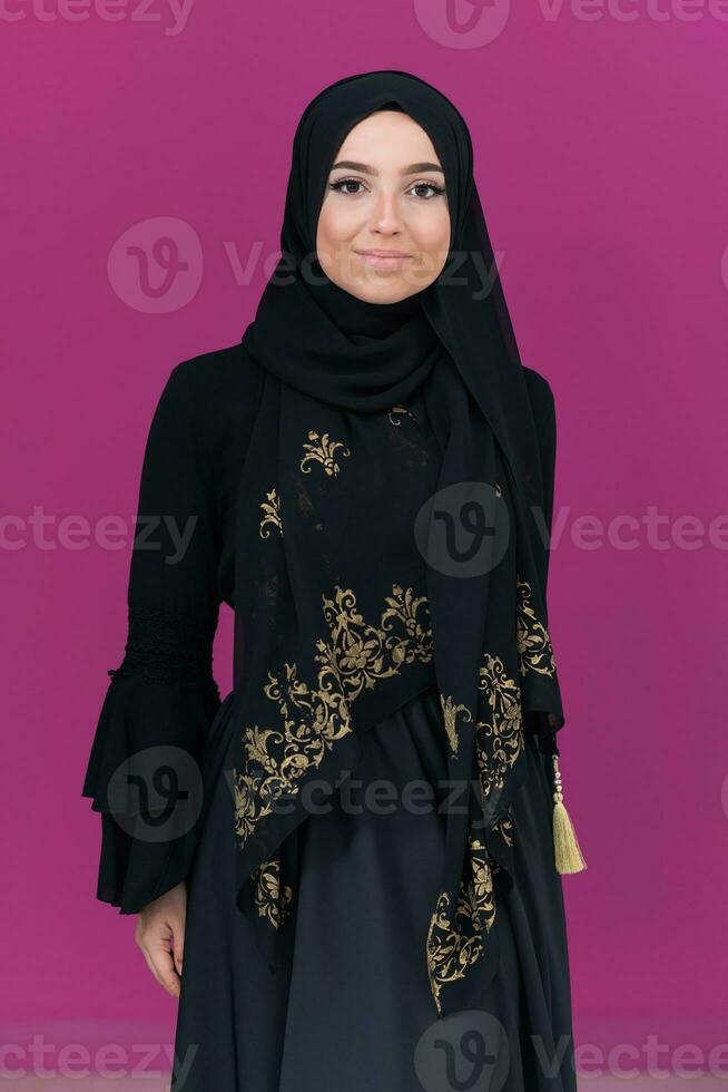 beautiful muslim woman in fashinable dress with hijab isolated on modern pink background representing concept of modern islam and ramadan kareem photo