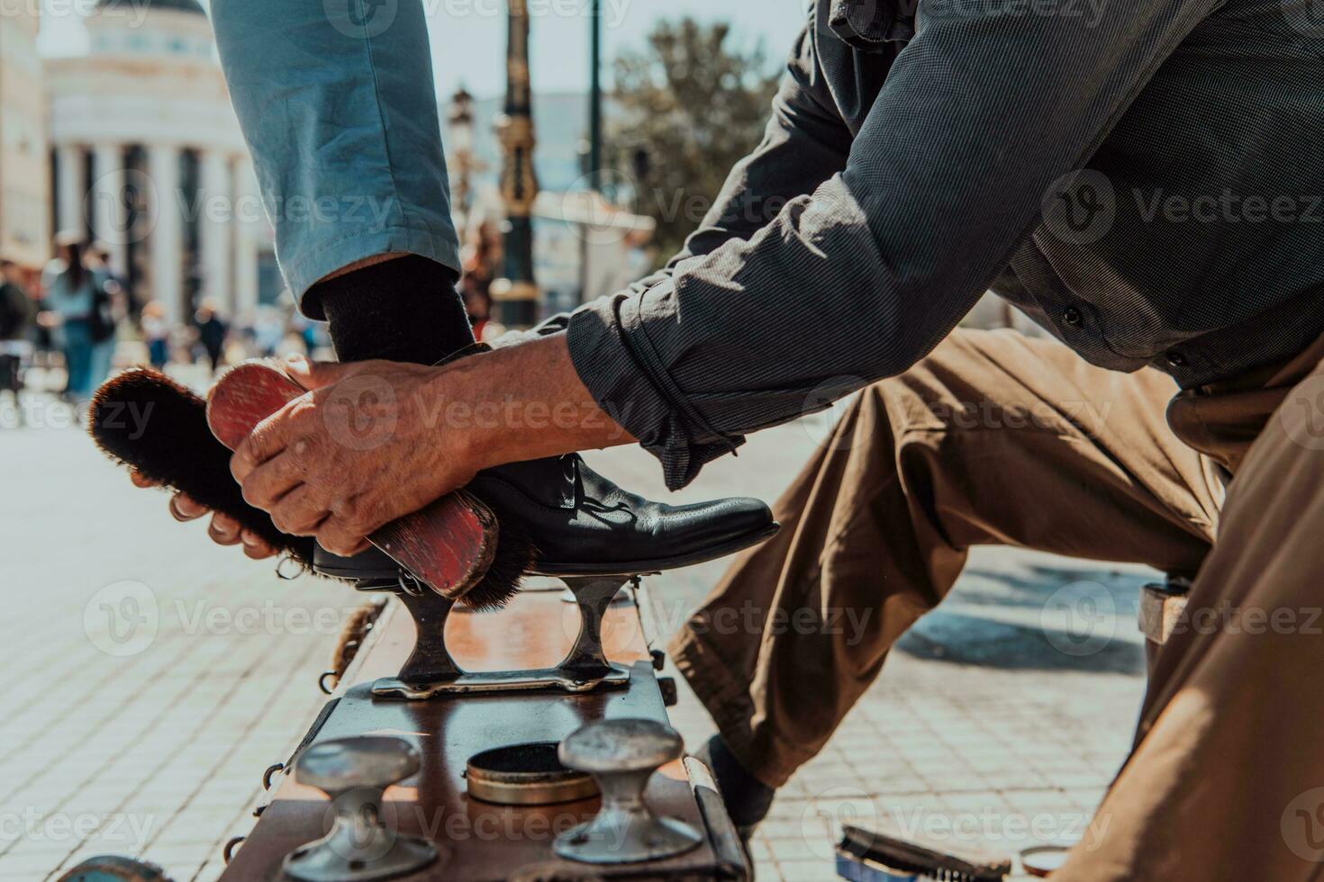 An old man hand polishing and painting a black shoe at street photo