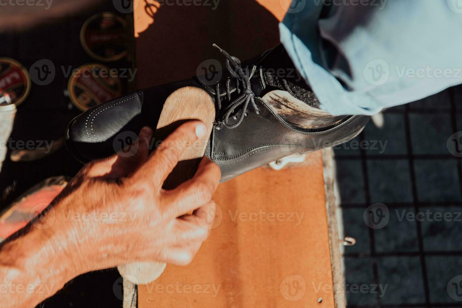 An old man hand polishing and painting a black shoe at street photo