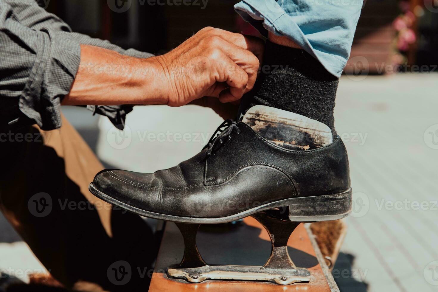 An old man hand polishing and painting a black shoe at street photo