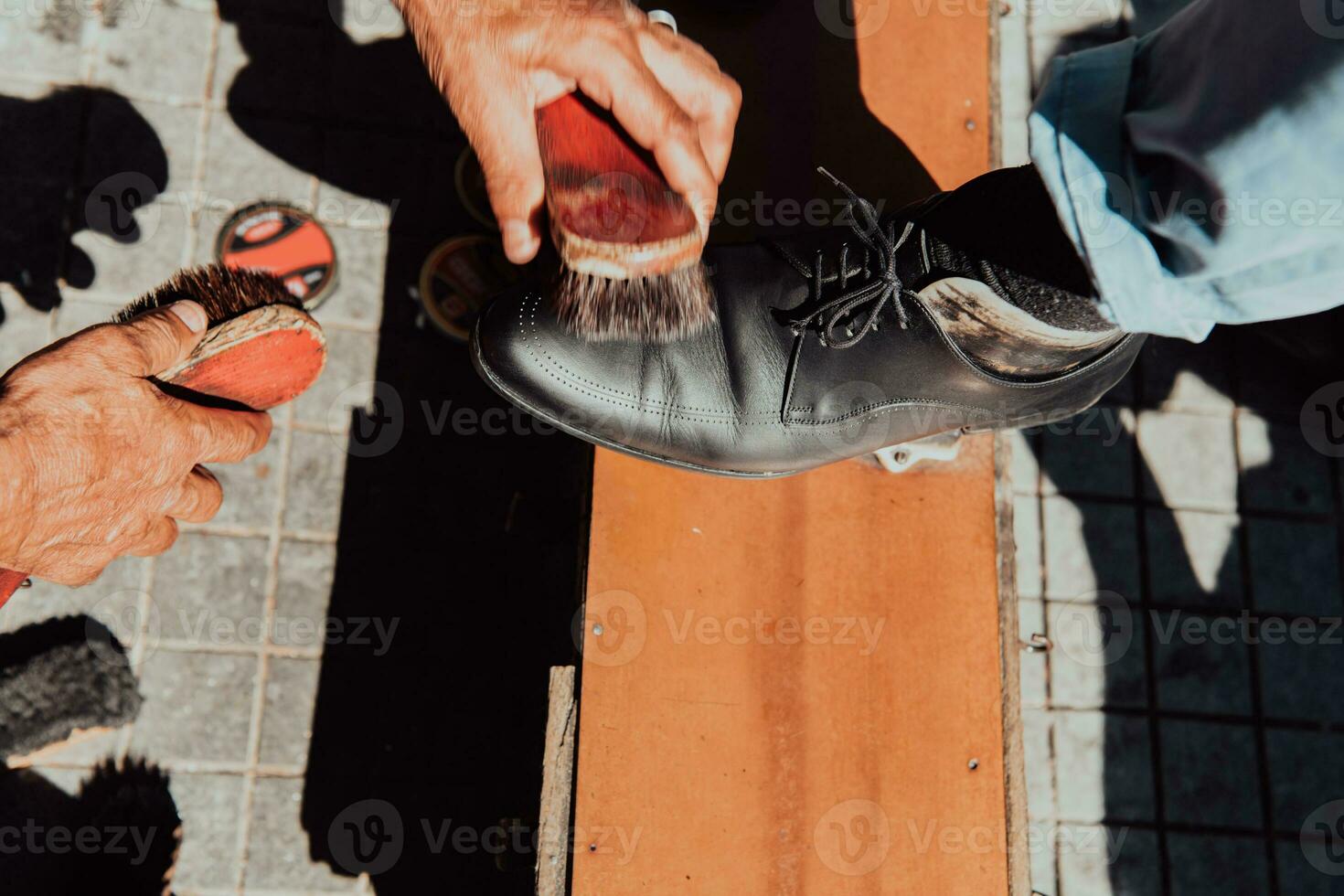 An old man hand polishing and painting a black shoe at street photo