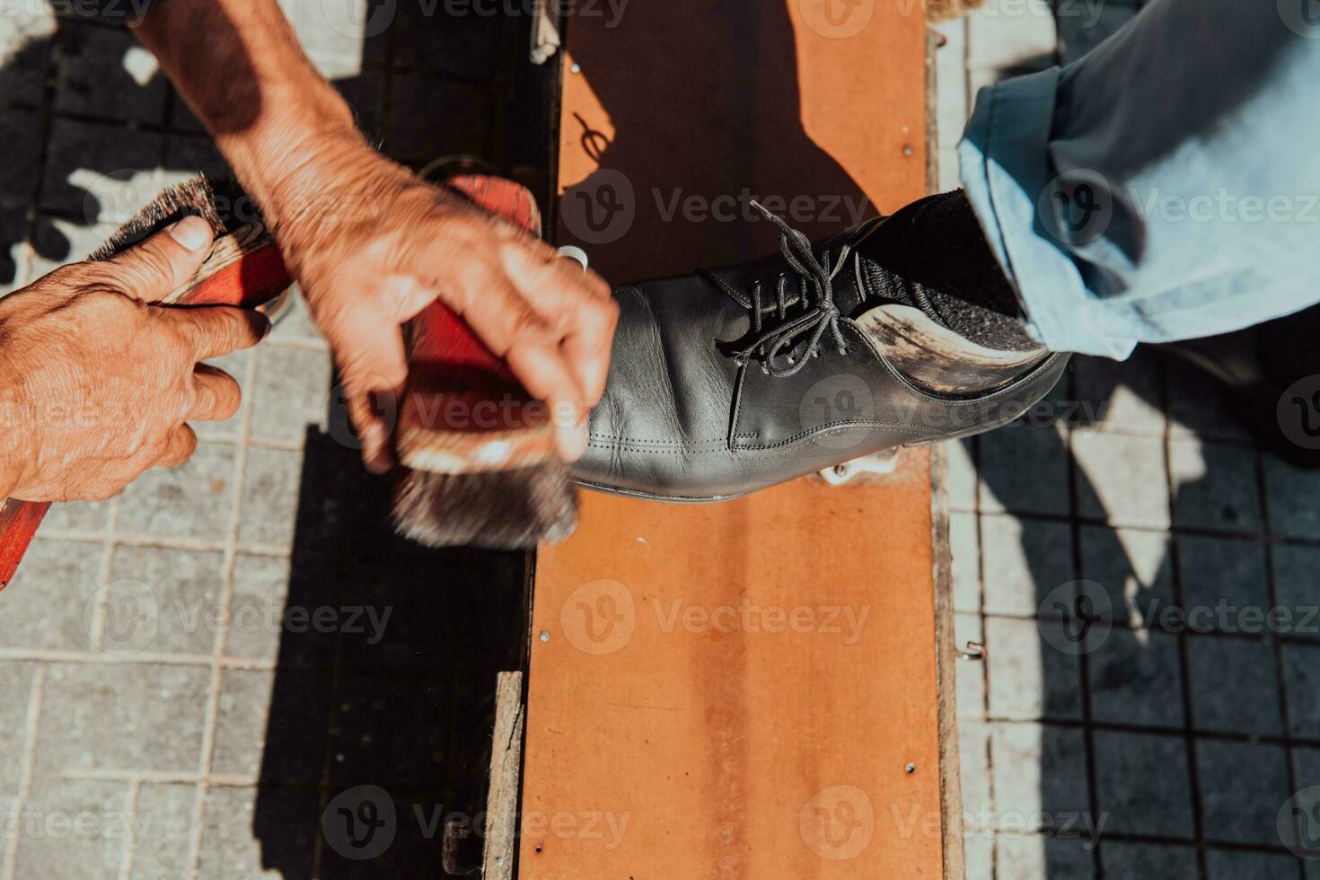 An old man hand polishing and painting a black shoe at street photo