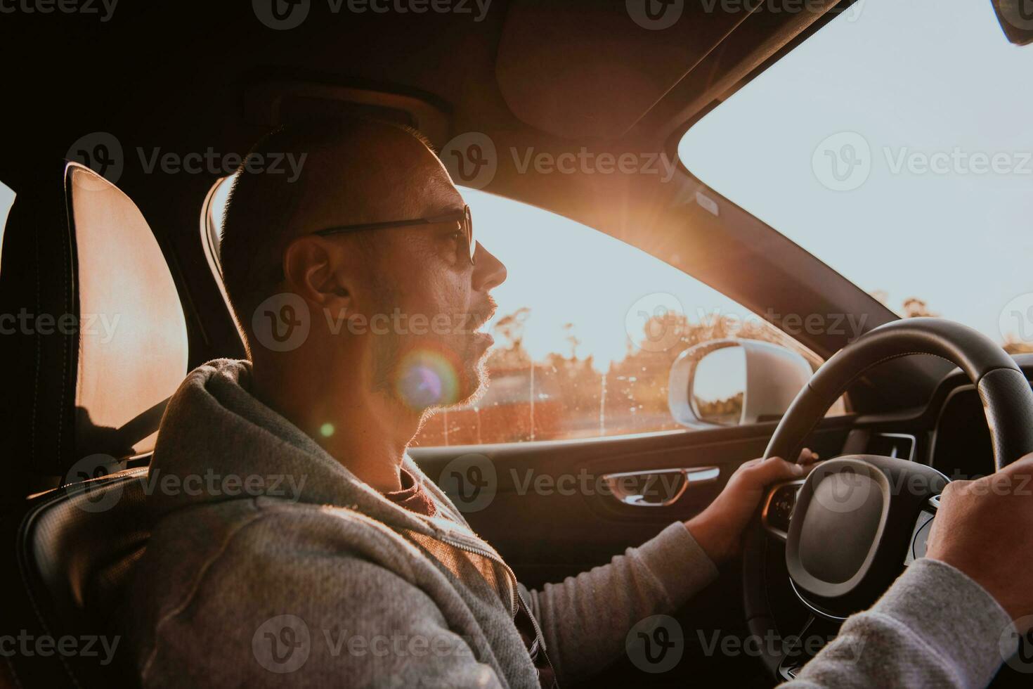 A man with a sunglasses driving a car at sunset. The concept of car travel photo
