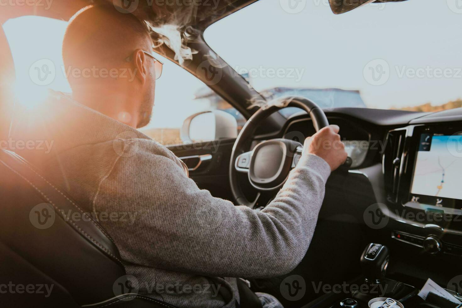 un hombre con un Gafas de sol conducción un coche a puesta de sol. el concepto de coche viaje foto