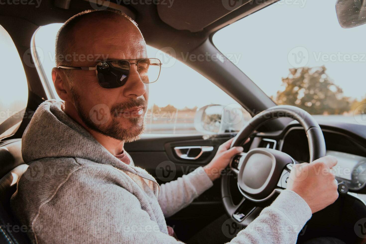 A man with a sunglasses driving a car at sunset. The concept of car travel photo