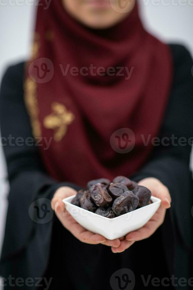 modern muslim woman holding a plate full of sweet dates on iftar time in ramadan kareem islamic healthy food concept photo