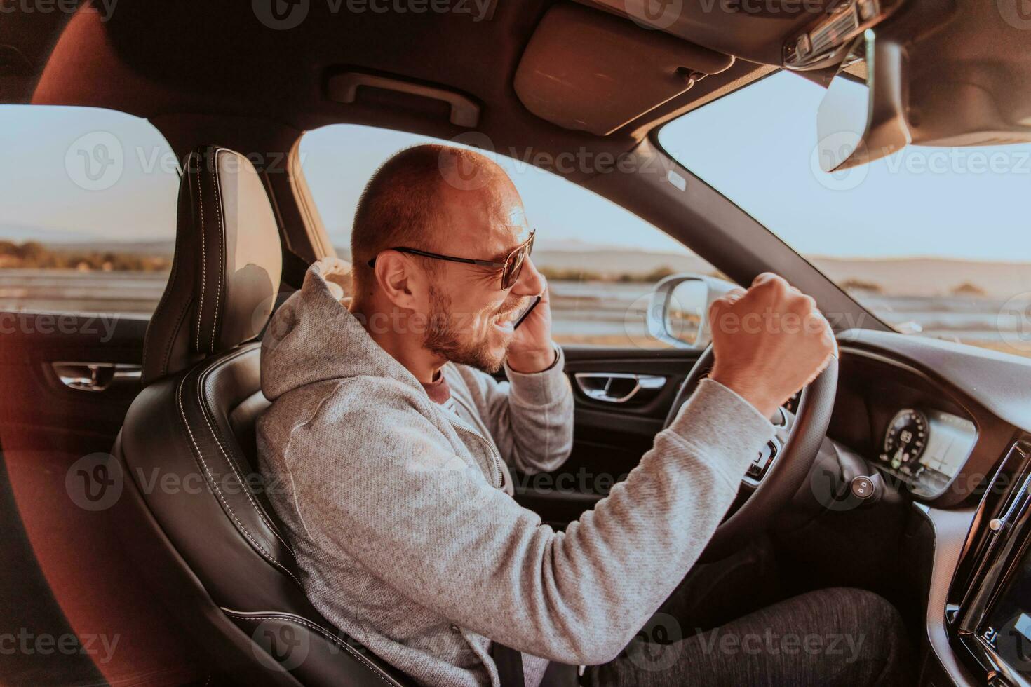 The driver receives happy information while talking on the smartphone while driving the car photo