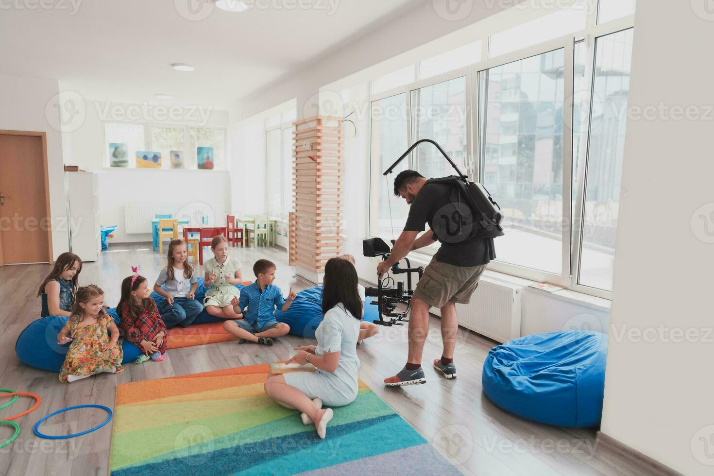 un camarógrafo con un profesional cámara registros para niños socializando en un preescolar institución foto