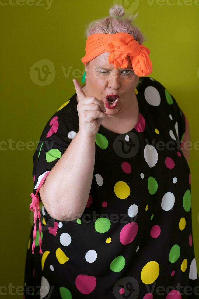 Mujer modelo sexy de talla grande con maquillaje de moda, rubia de moda con vestido corto negro posando en el fondo verde del estudio. foto