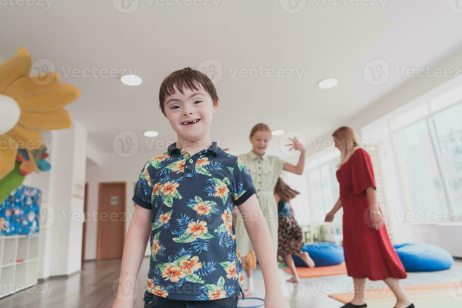 Small nursery school children with female teacher on floor indoors in classroom, doing exercise. Jumping over hula hoop circles track on the floor. photo