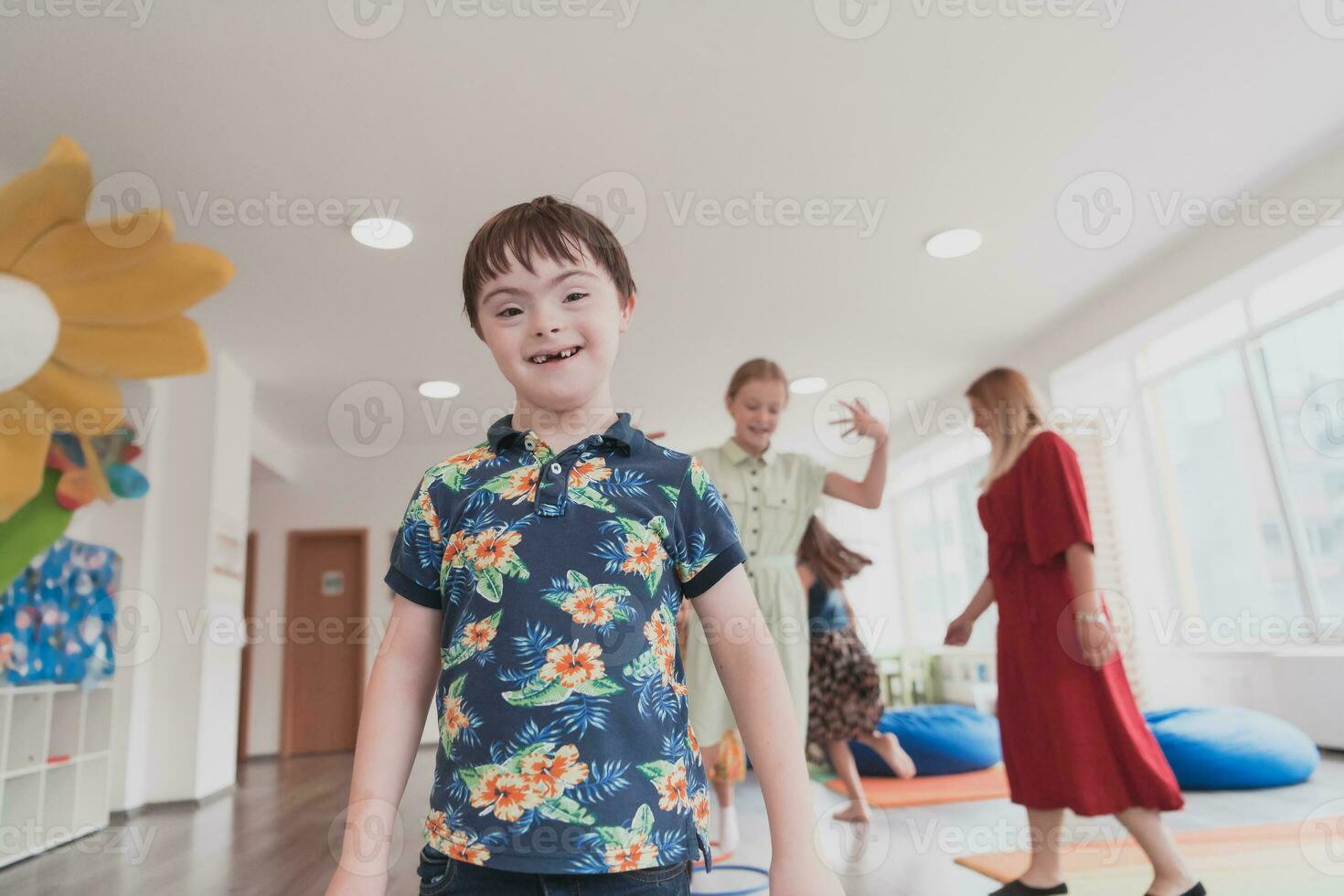 pequeño guardería colegio niños con hembra profesor en piso adentro en aula, haciendo ejercicio. saltando terminado hula aro círculos pista en el piso. foto