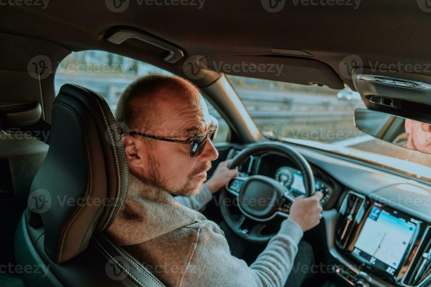 un hombre con un Gafas de sol conducción un coche a puesta de sol. el concepto de coche viaje foto