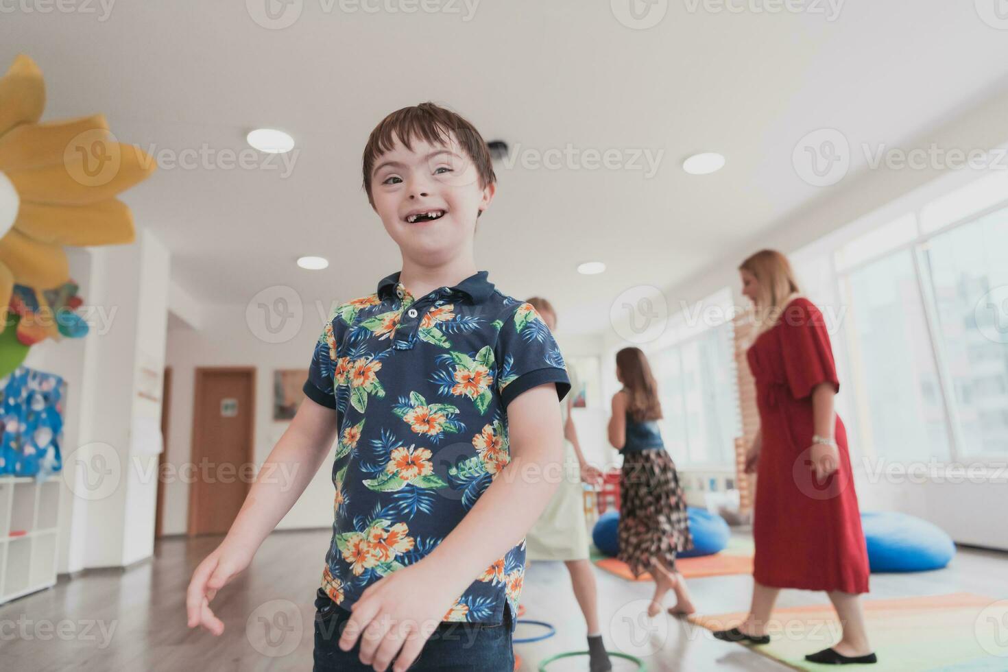 pequeño guardería colegio niños con hembra profesor en piso adentro en aula, haciendo ejercicio. saltando terminado hula aro círculos pista en el piso. foto