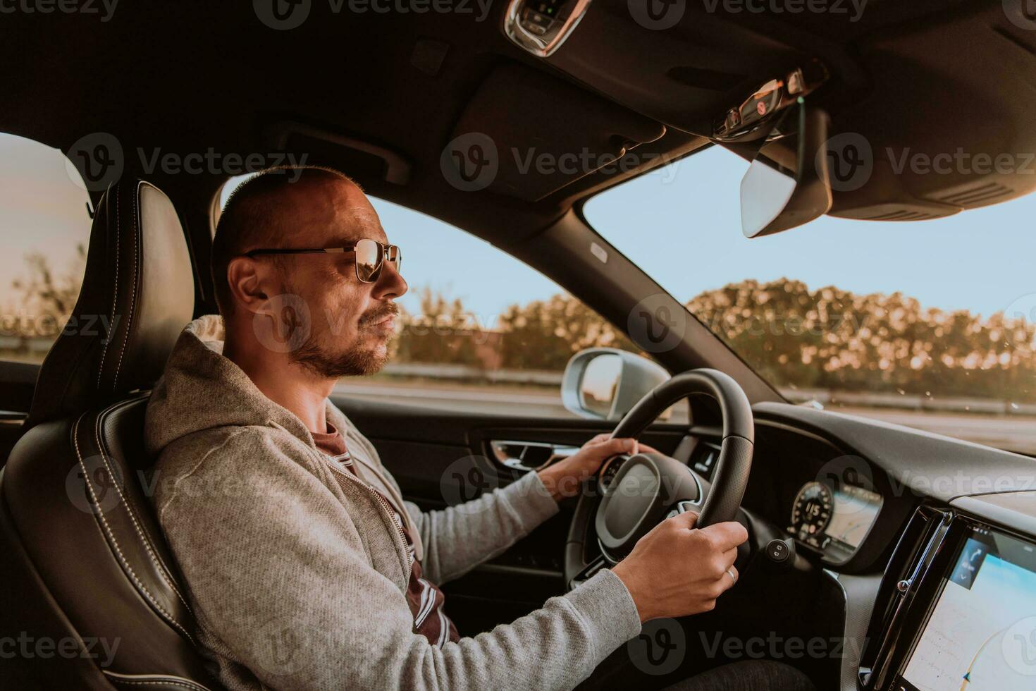 A man with a sunglasses driving a car at sunset. The concept of car travel photo