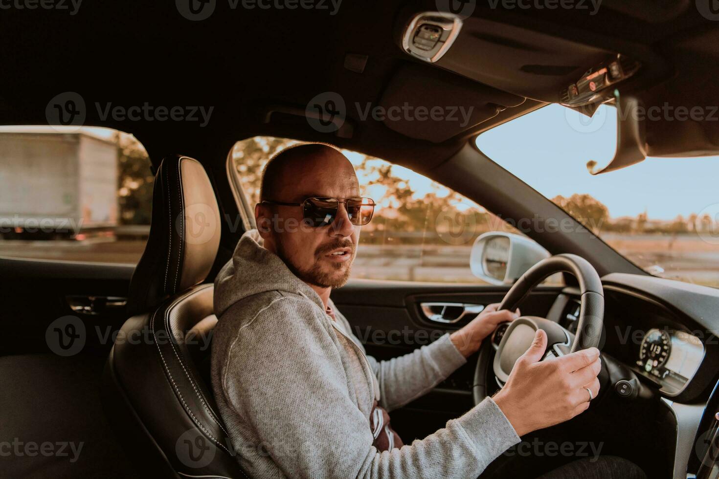 un hombre con un Gafas de sol conducción un coche a puesta de sol. el concepto de coche viaje foto