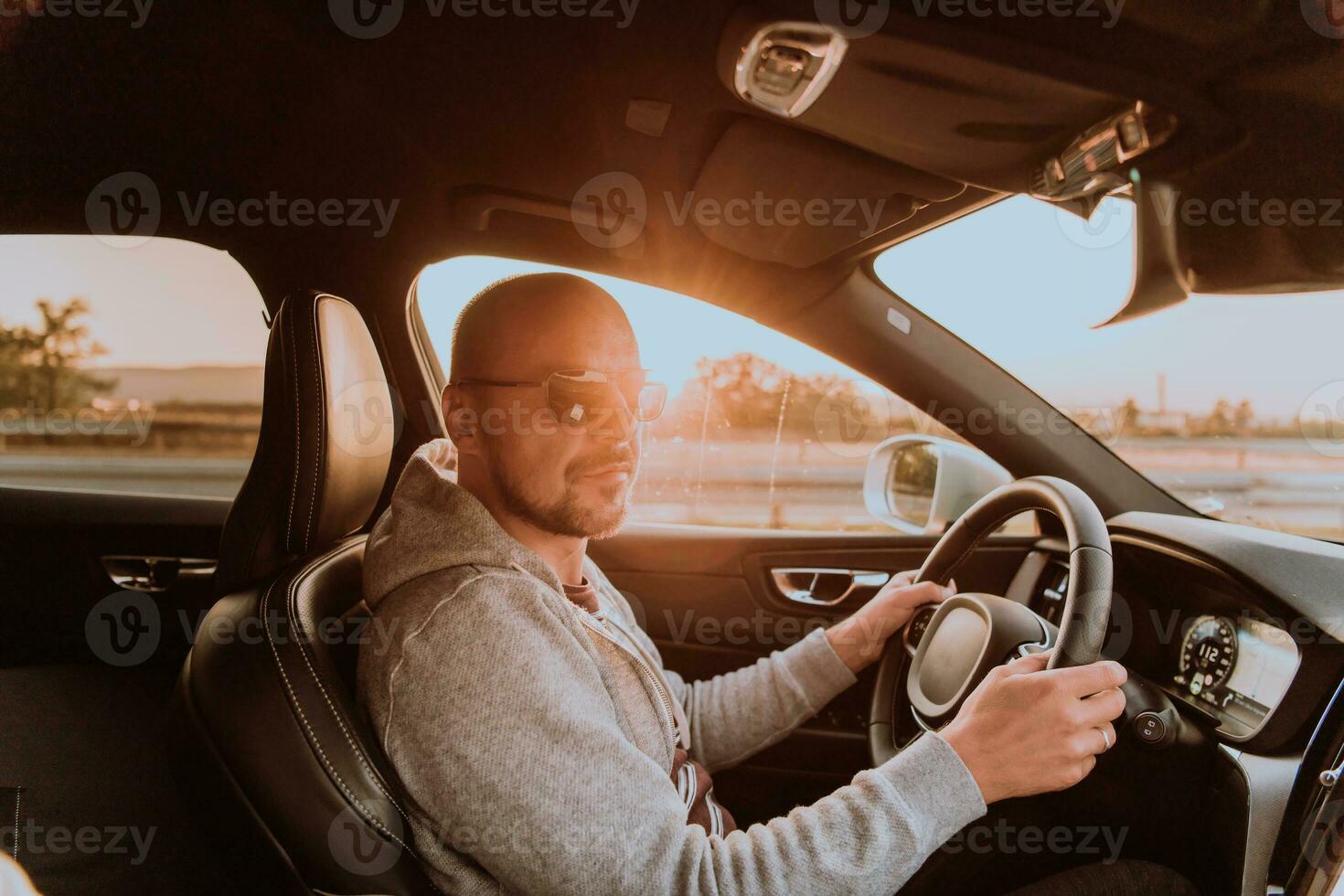 A man with a sunglasses driving a car at sunset. The concept of car travel photo