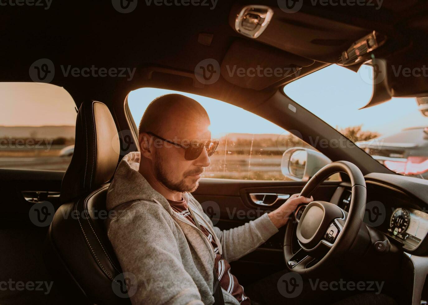 A man with a sunglasses driving a car at sunset. The concept of car travel photo