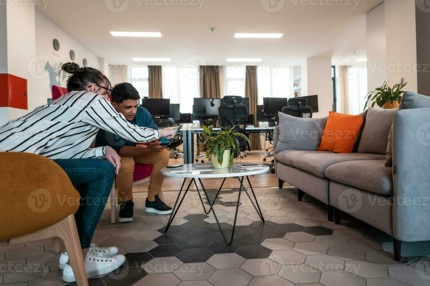 Group of casual multiethnic business people taking break from the work doing different things while enjoying free time in relaxation area at modern open plan startup office photo