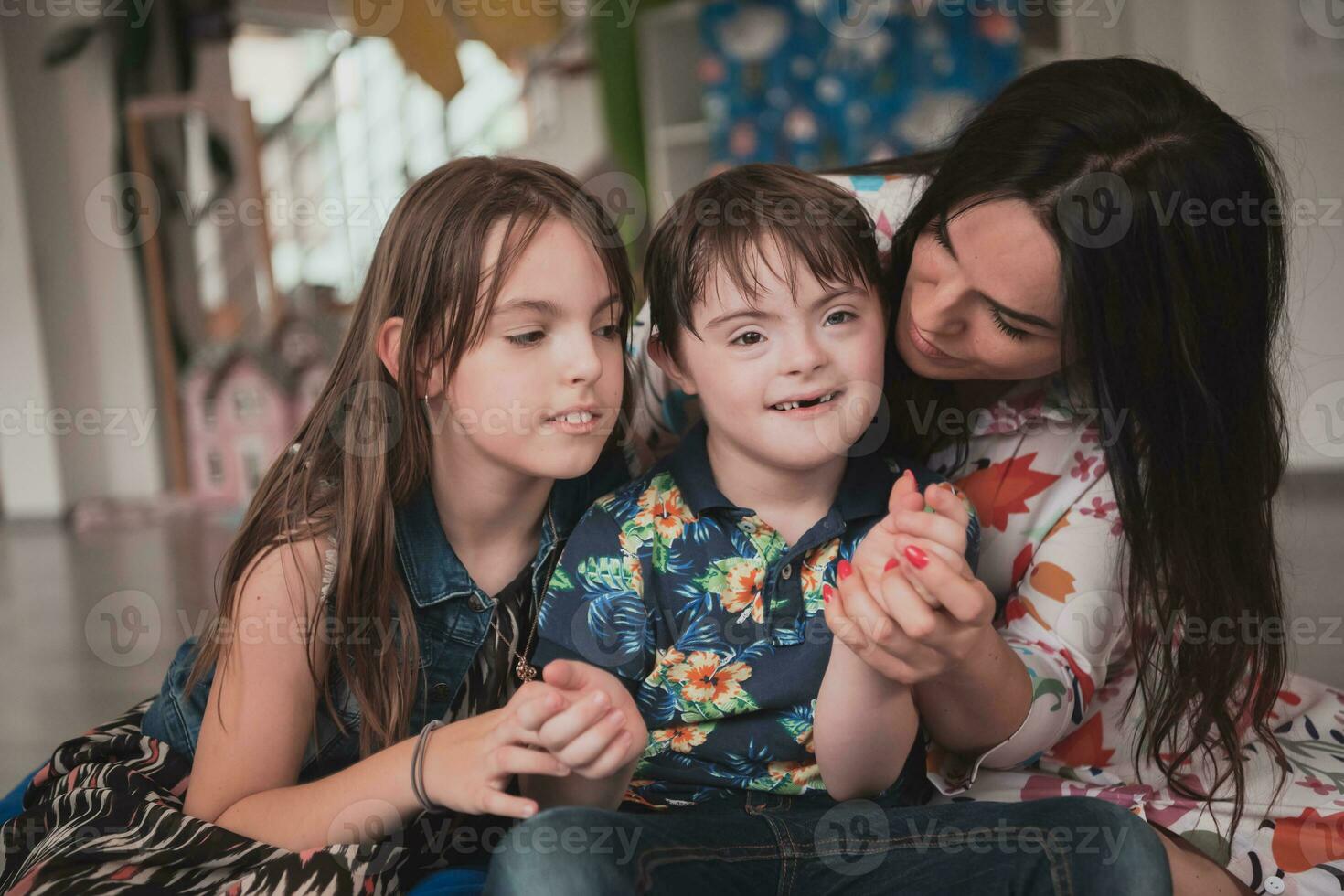 un niña y un mujer abrazo un niño con abajo síndrome en un moderno preescolar institución foto