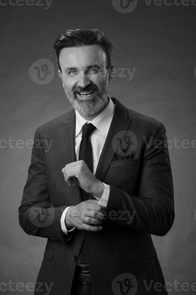 retrato de un elegante hombre de negocios de alto nivel con barba y ropa informal de negocios en un estudio fotográfico aislado en un fondo oscuro gesticulando con las manos foto