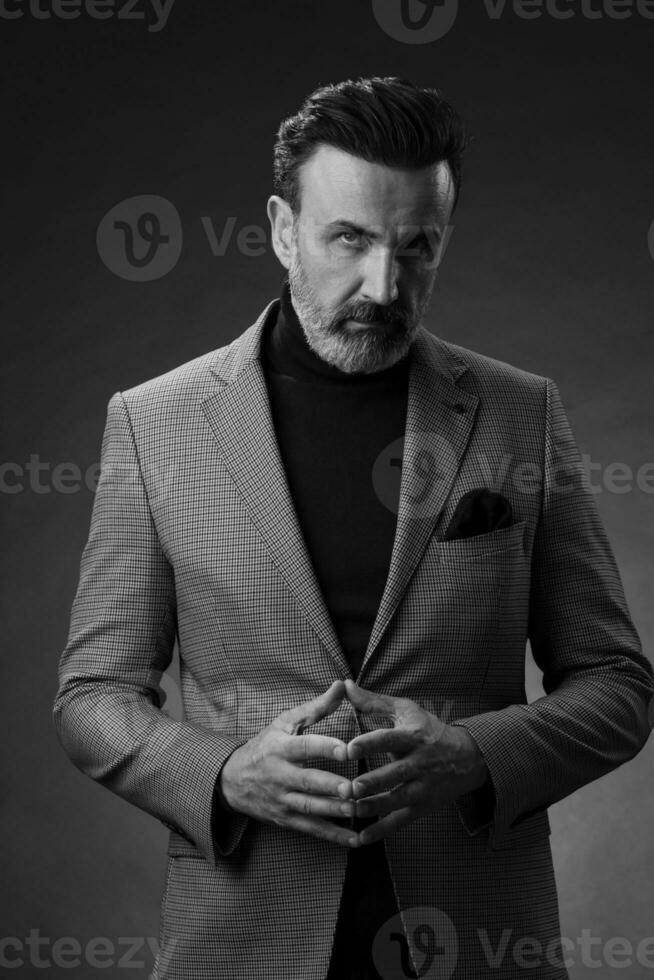 retrato de un elegante hombre de negocios de alto nivel con barba y ropa informal de negocios en un estudio fotográfico aislado en un fondo oscuro gesticulando con las manos foto