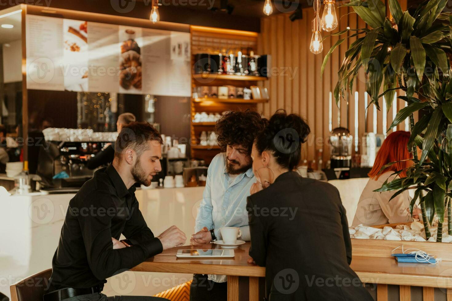 A group of friends hanging out in a cafe, and among them is a tablet. photo