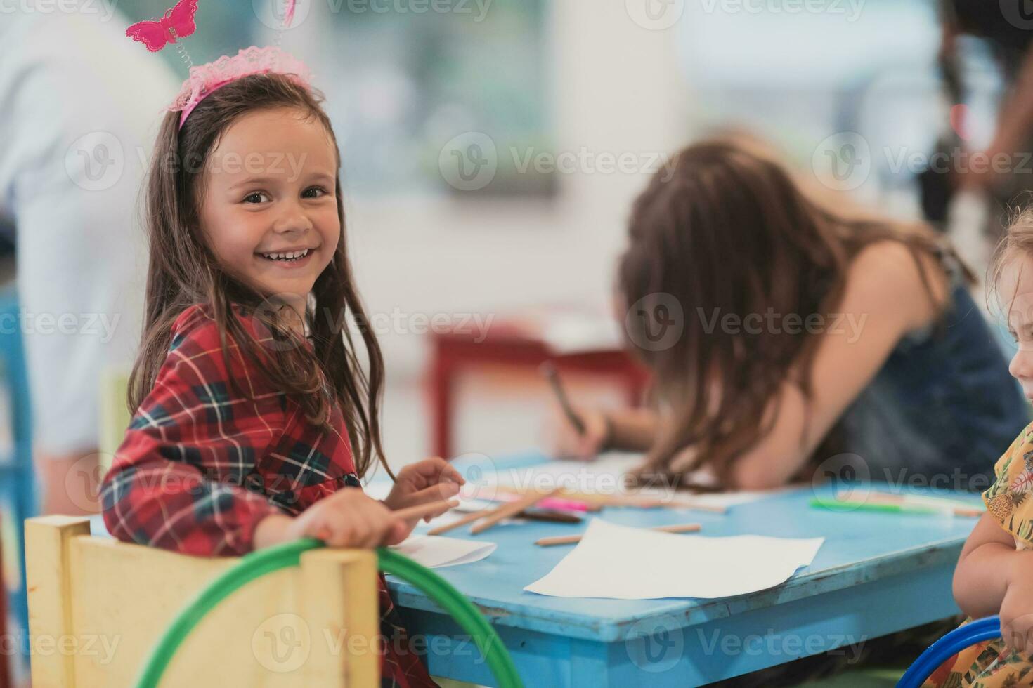 Creative kids during an art class in a daycare center or elementary school classroom drawing with female teacher. photo