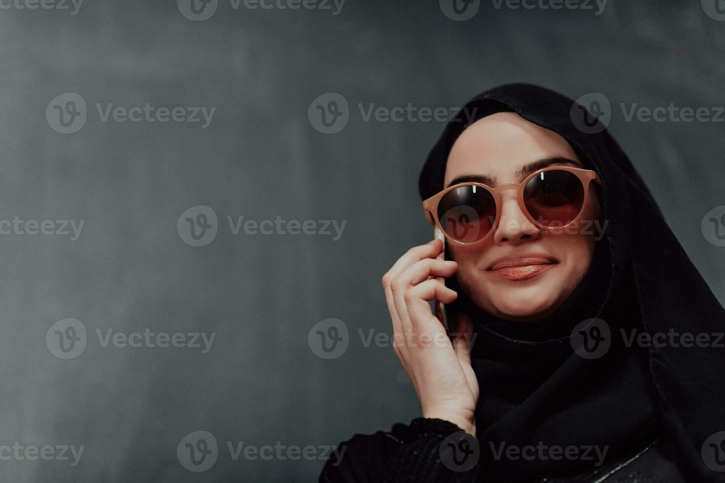 Young modern muslim business woman using smartphone wearing hijab clothes in front of black chalkboard photo