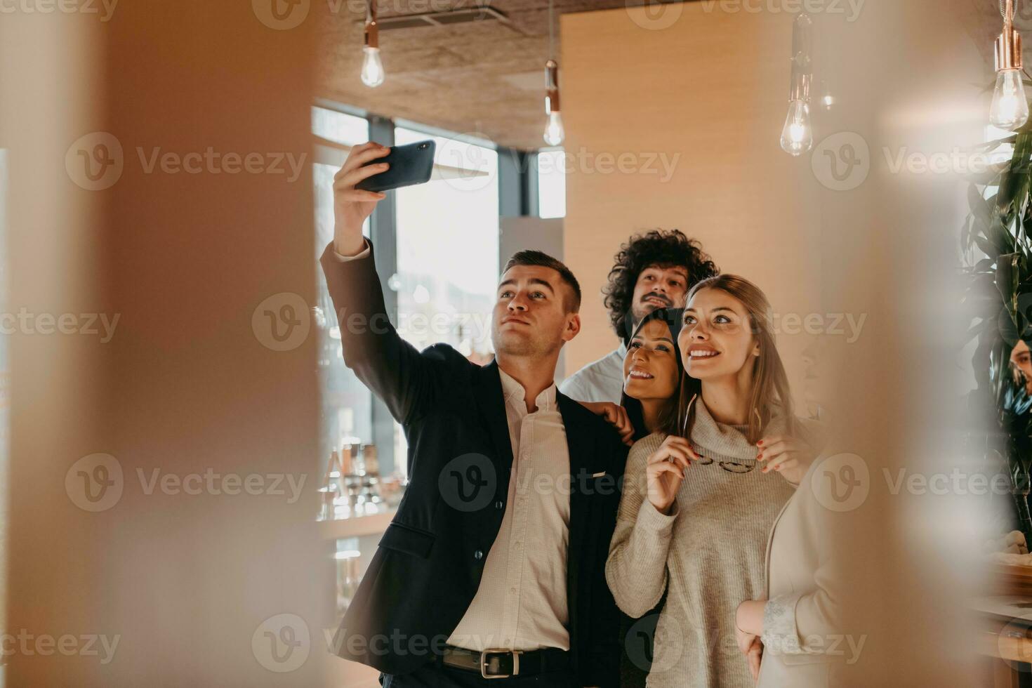 Group of cheerful colleagues taking selfie and gesturing while standing in the modern office. photo