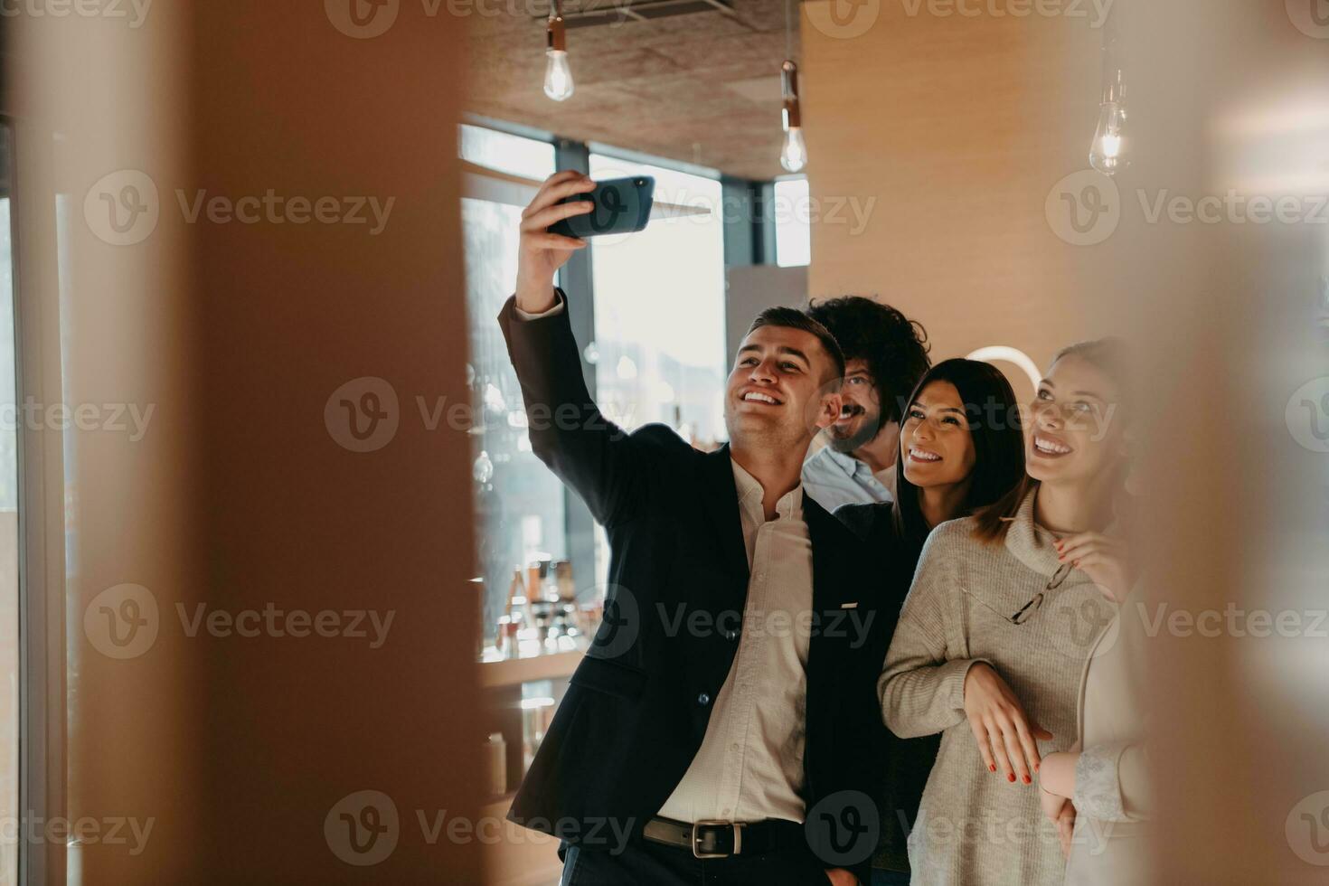 Group of cheerful colleagues taking selfie and gesturing while standing in the modern office. photo