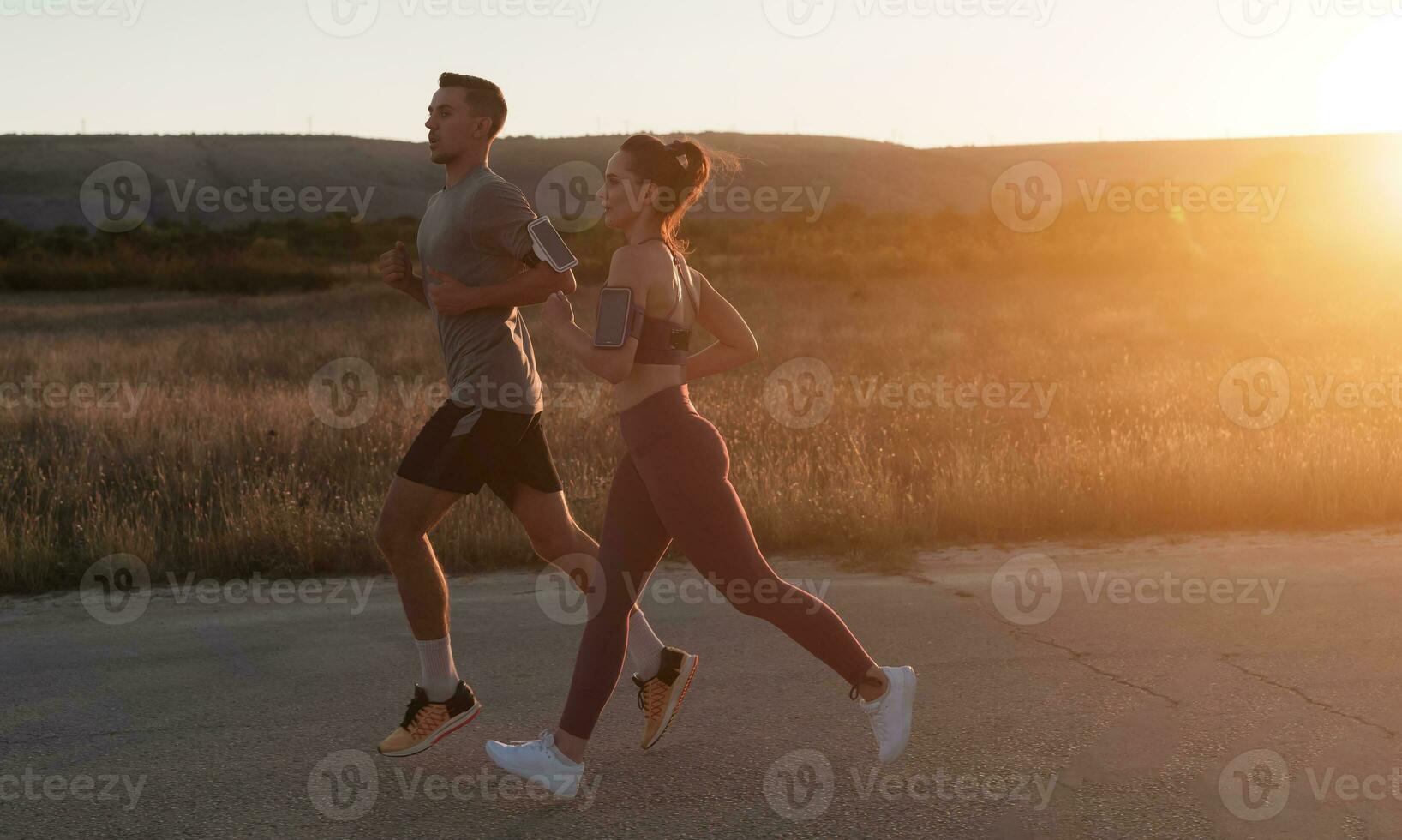 healthy young couple jogging in the city streets in the early morning with a beautiful sunrise in the background. photo